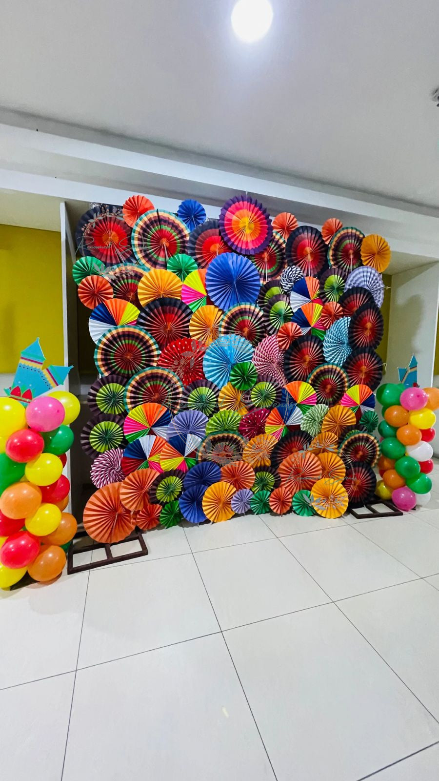 Vibrant Paper Fan Holi Backdrop with Balloon Pillars – Festive Photo Booth Decor