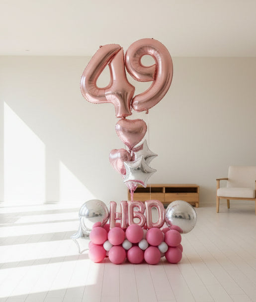 A balloon bouquet with a '49' birthday foil balloon and accompanying pink balloons and decorations