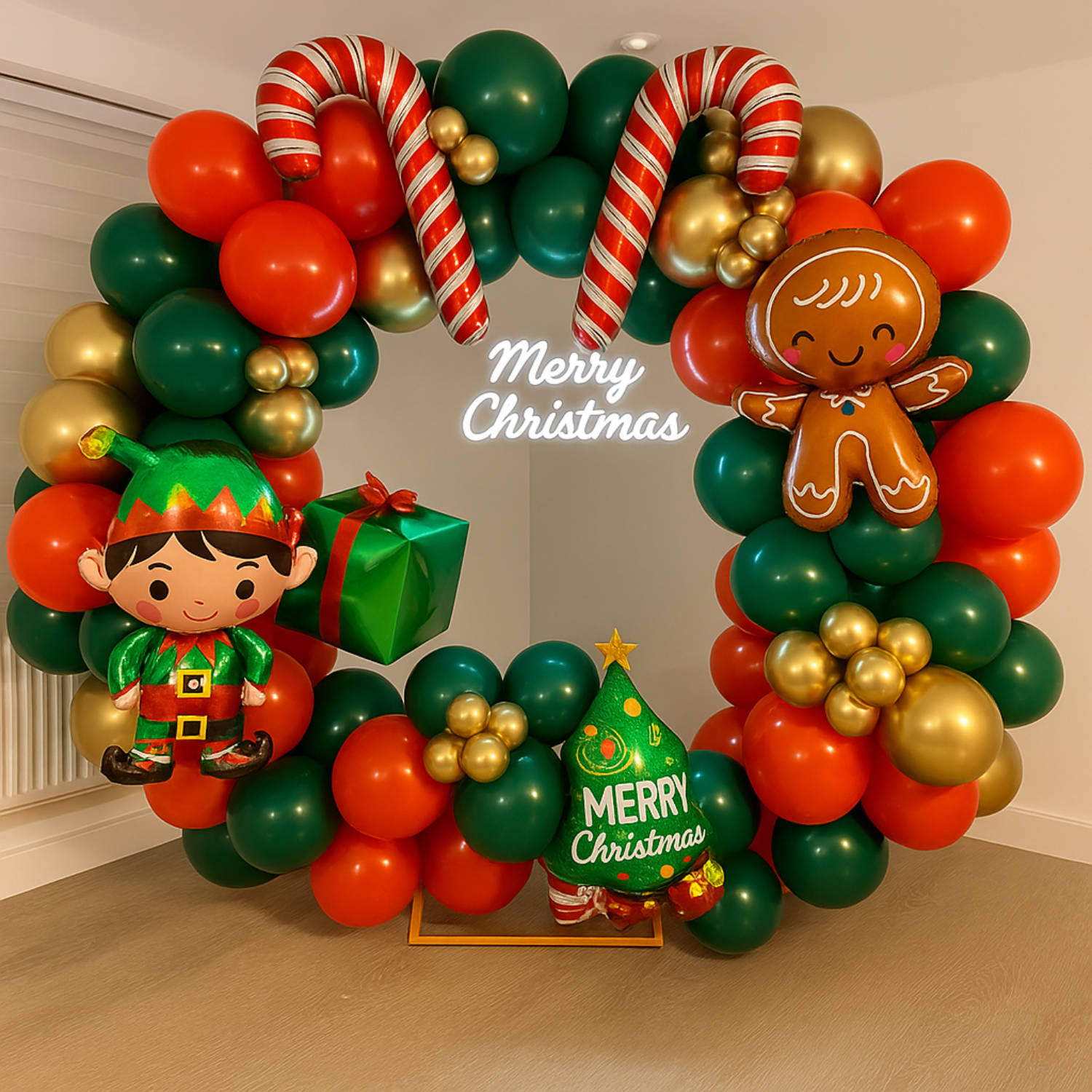 Christmas balloon decoration with red, green, and gold balloon arch featuring elf, gingerbread man, candy canes, and Merry Christmas sign.