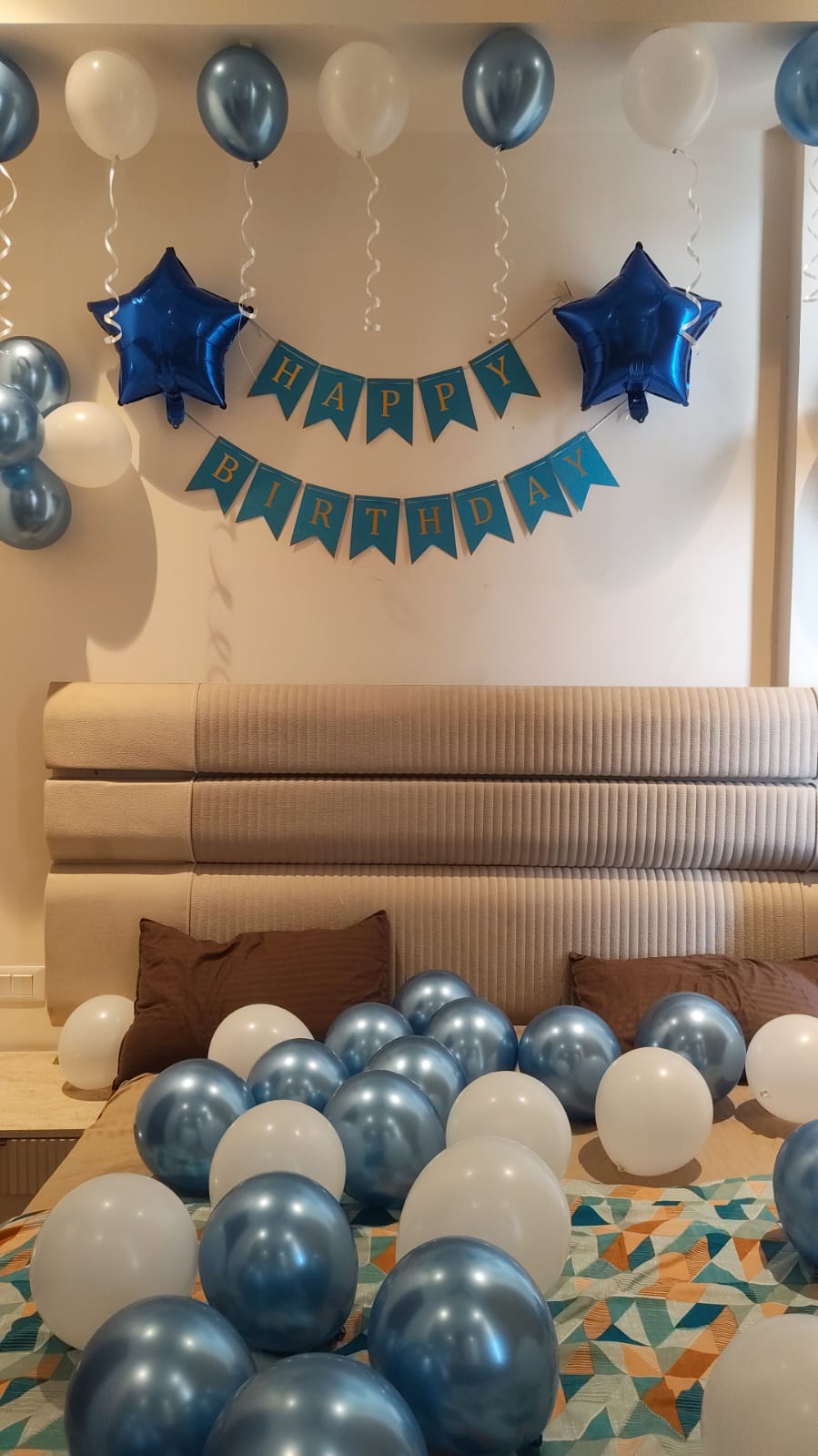 Blue and white birthday room decoration with ceiling balloons, star foil balloons, Happy Birthday banner and balloon bed setup.