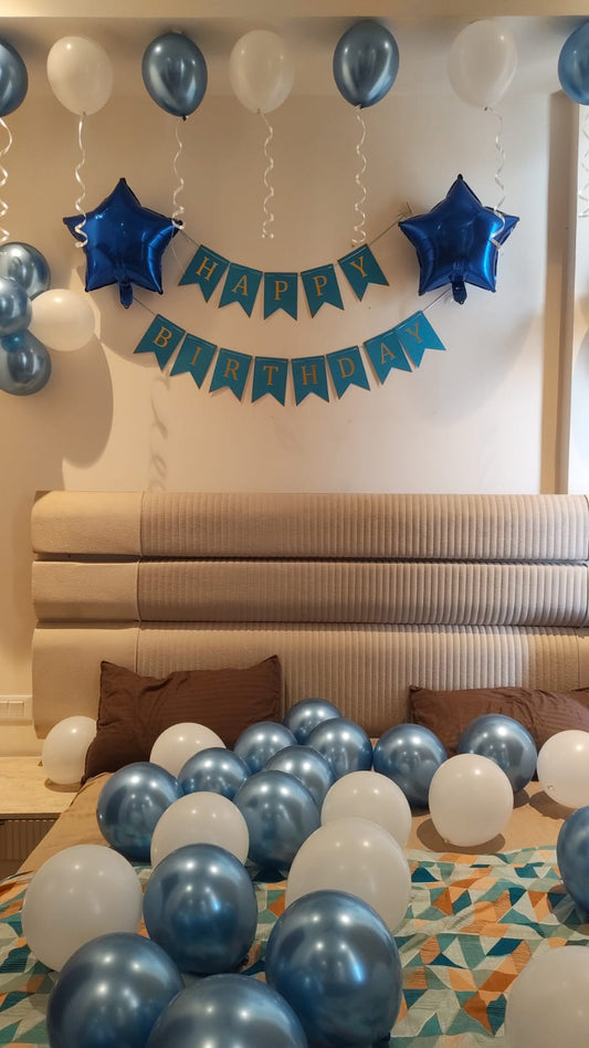 Blue and white birthday room decoration with ceiling balloons, star foil balloons, Happy Birthday banner and balloon bed setup.