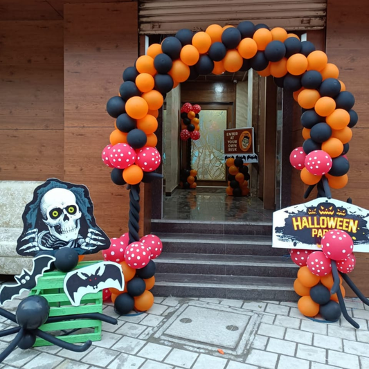 Halloween balloon arch entrance decorated with black and orange balloons, skeleton cutout, spider prop and bat accents for party decoration.