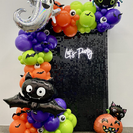 Halloween balloon backdrop with black sequin wall, pumpkins and bats for parties