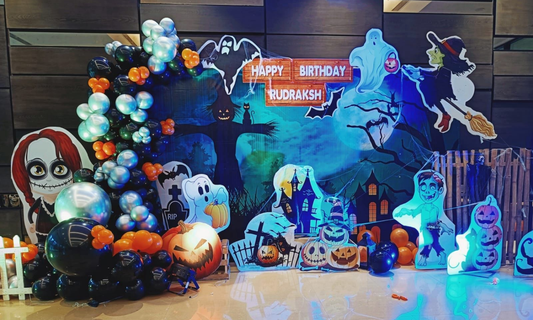 Halloween birthday balloon backdrop with ghosts, pumpkins, witch on broom, zombie cutout and balloon garland for party decoration.