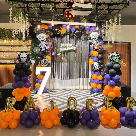 Halloween birthday stage decoration with balloon arch, skeleton props, happy birthday backdrop and customized balloon letters for kids’ party.