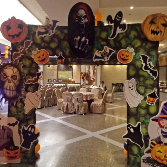 Halloween entrance arch decorated with ghosts, pumpkins, bats, skull props and spooky cutouts for party decoration.