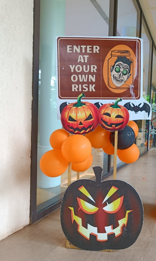 Halloween entrance decoration with orange and black balloons, pumpkin cutouts, and ‘Enter at Your Own Risk’ sign for party décor.