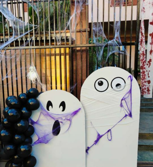 Halloween ghost backdrop with black balloon garland, cobwebs and spooky ghost props for party decoration.