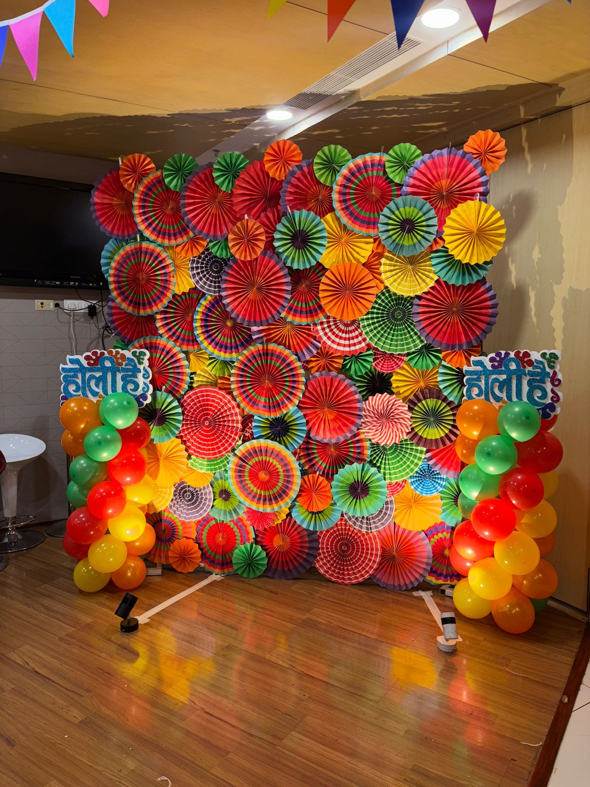 Vibrant Paper Fan Holi Backdrop with Balloon Pillars – Festive Photo Booth Decor