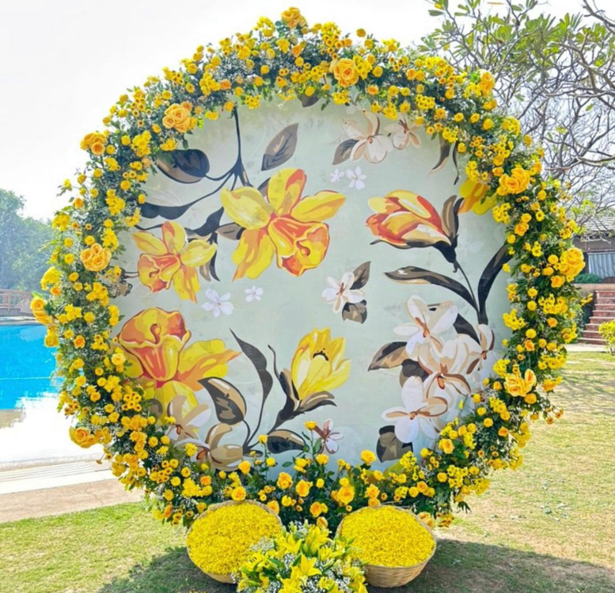 Round yellow floral backdrop decorated with fresh yellow flowers at an outdoor event.