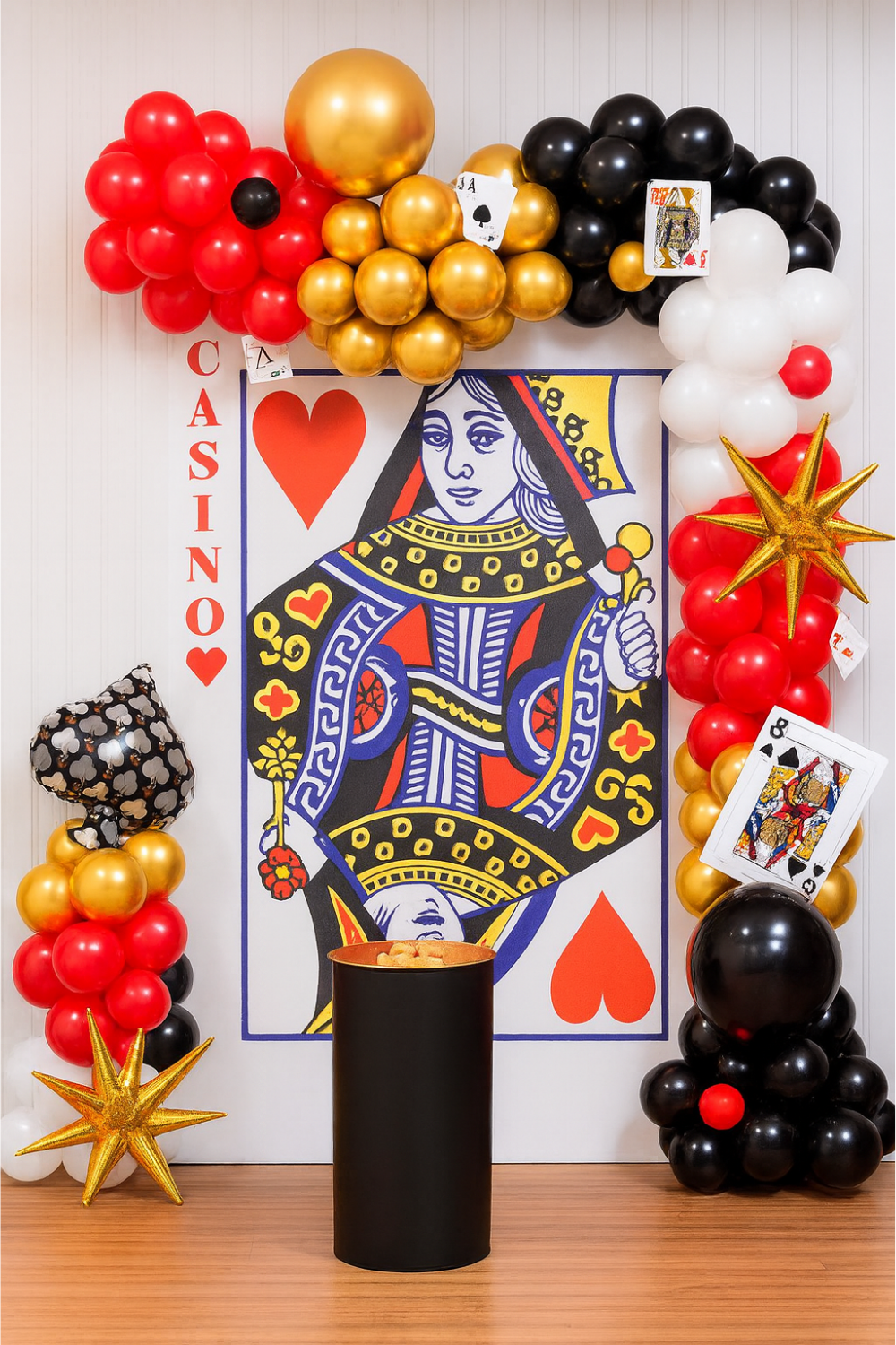 Queen of Hearts casino-themed balloon decoration backdrop with red, black, gold, and white balloons and playing card accents.