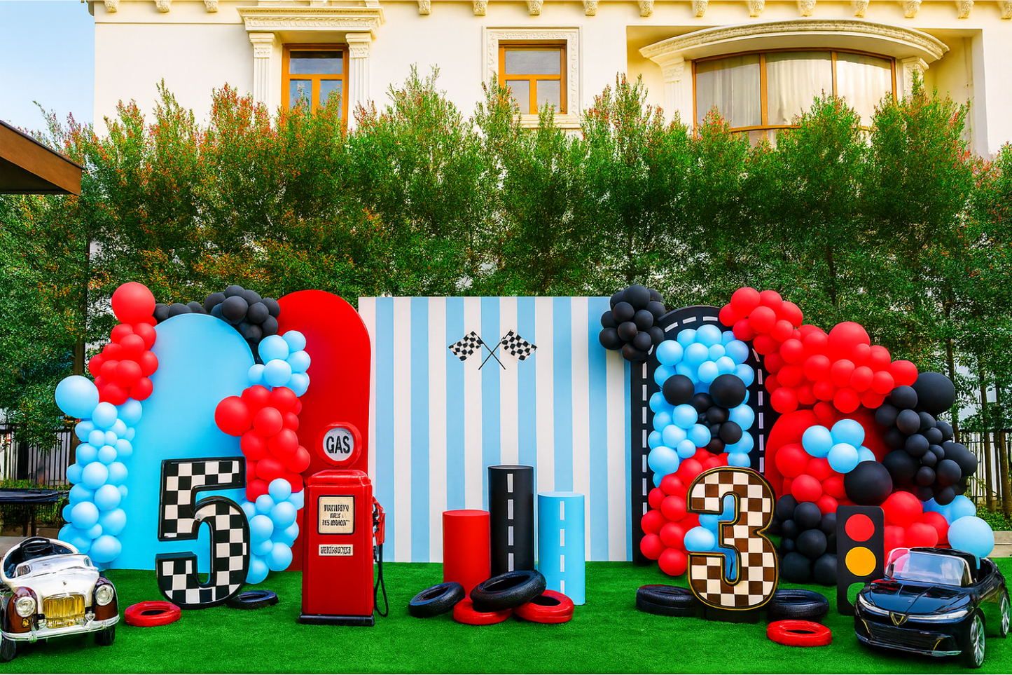 Race car-themed birthday decoration with red, blue, and black balloons, checkered numbers, gas station prop, and toy cars.