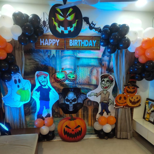 Halloween birthday balloon backdrop with ghost cutout, pumpkins, zombie figure, cartoon props and balloon garlands for kids’ party decoration.