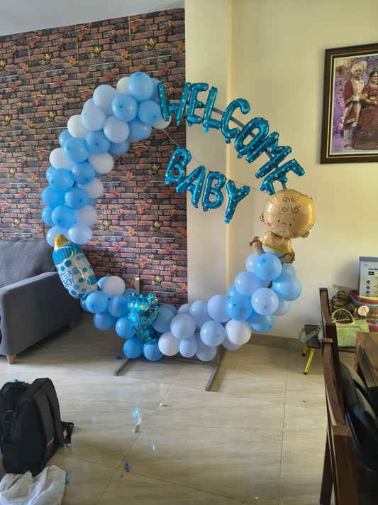 Welcome baby boy balloon ring decoration setup at home with blue and white balloons and foil welcome baby letters.